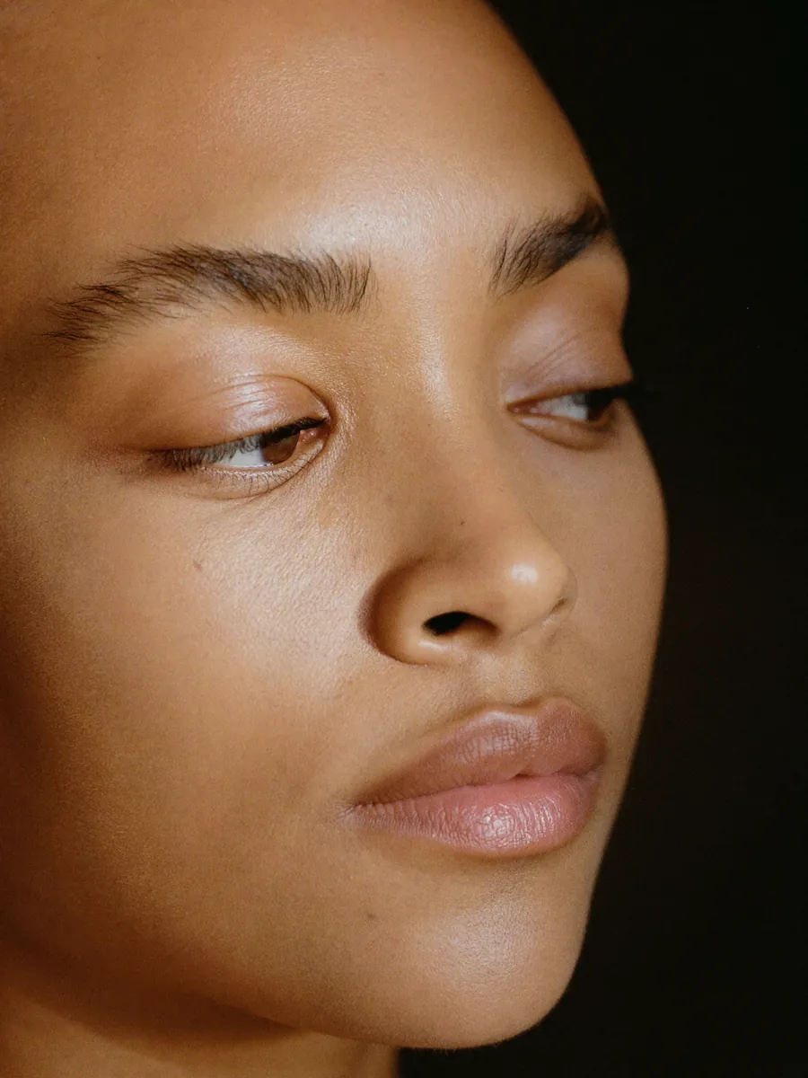 A brow being shaped with cotton thread, close up